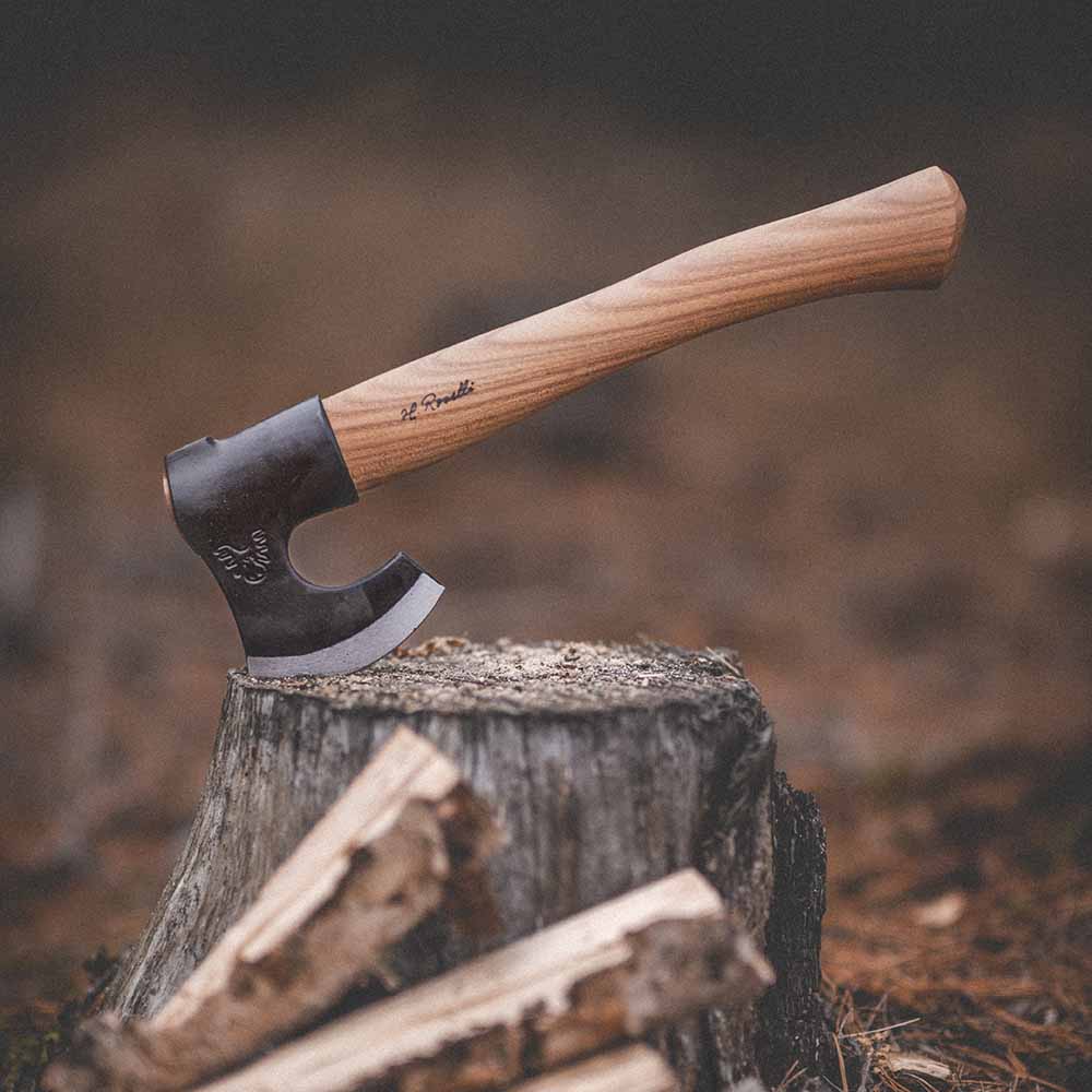 Compact hunting axe with wooden handle, embedded in tree stump for outdoor use