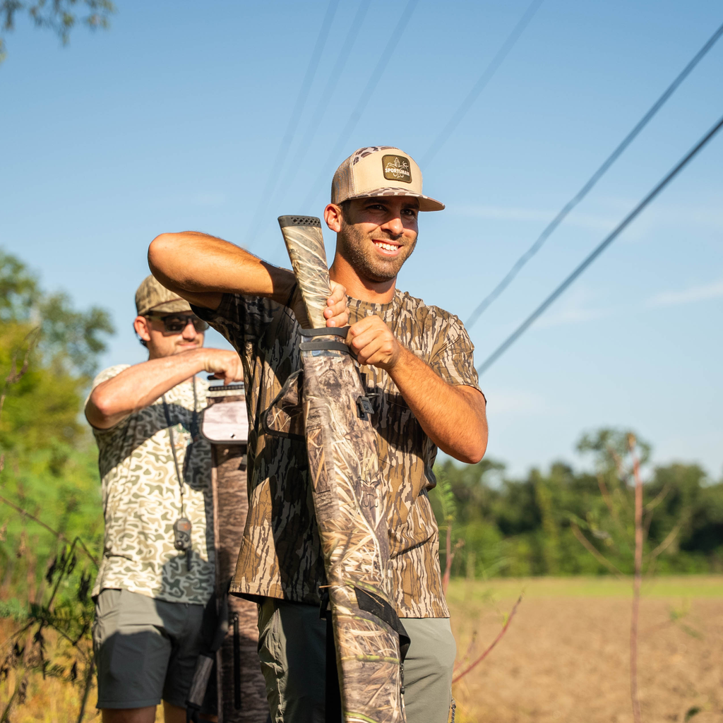 Man in camo holding shotgun with camo gun sleeve, outdoor hunting gear