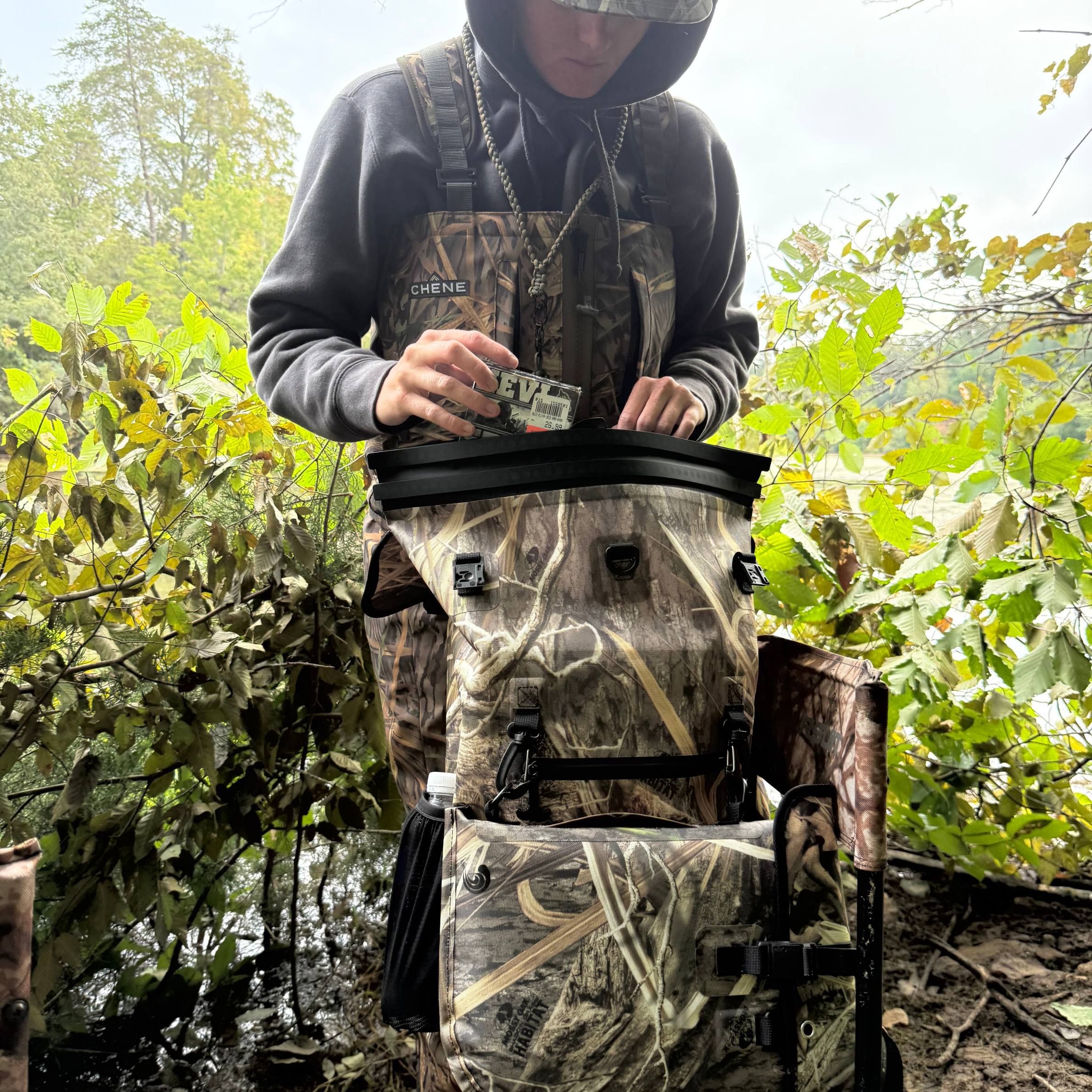 Camo hunting backpack with dry storage, used in woodland setting for outdoor gear organization