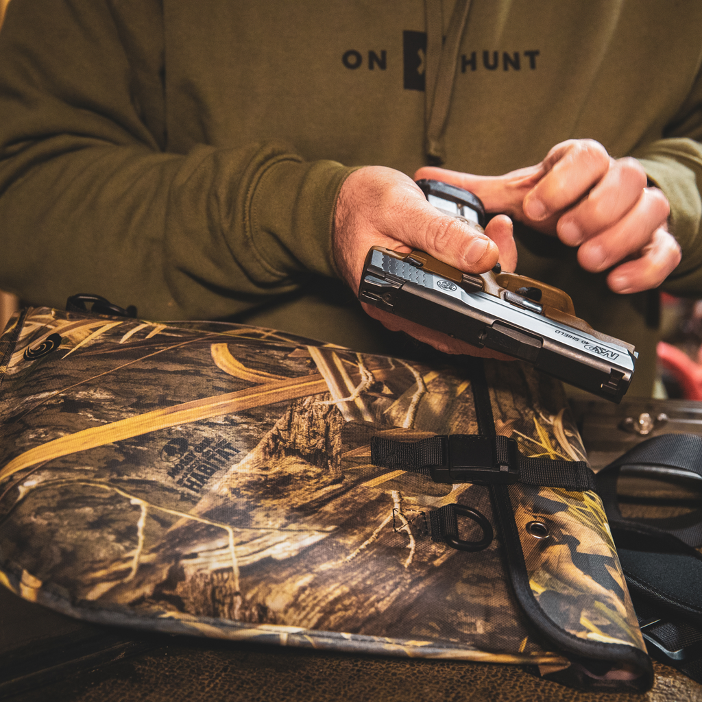Camo hunting gear bag with Mossy Oak pattern, holding handgun for outdoor use