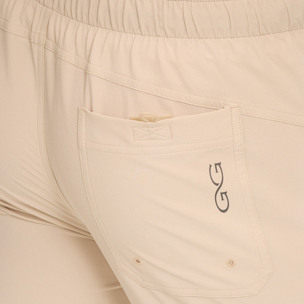 Beige hunting pants with elastic waist, rear pocket, and logo detail for outdoor use