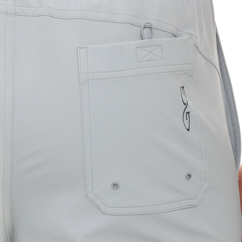 Light gray hunting pants with utility pocket, reinforced stitching, and drainage grommets for outdoor use