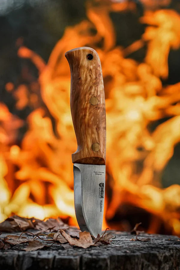 Helle Waldhorn hunting knife with wooden handle, stainless steel blade, set against campfire glow for outdoor use
