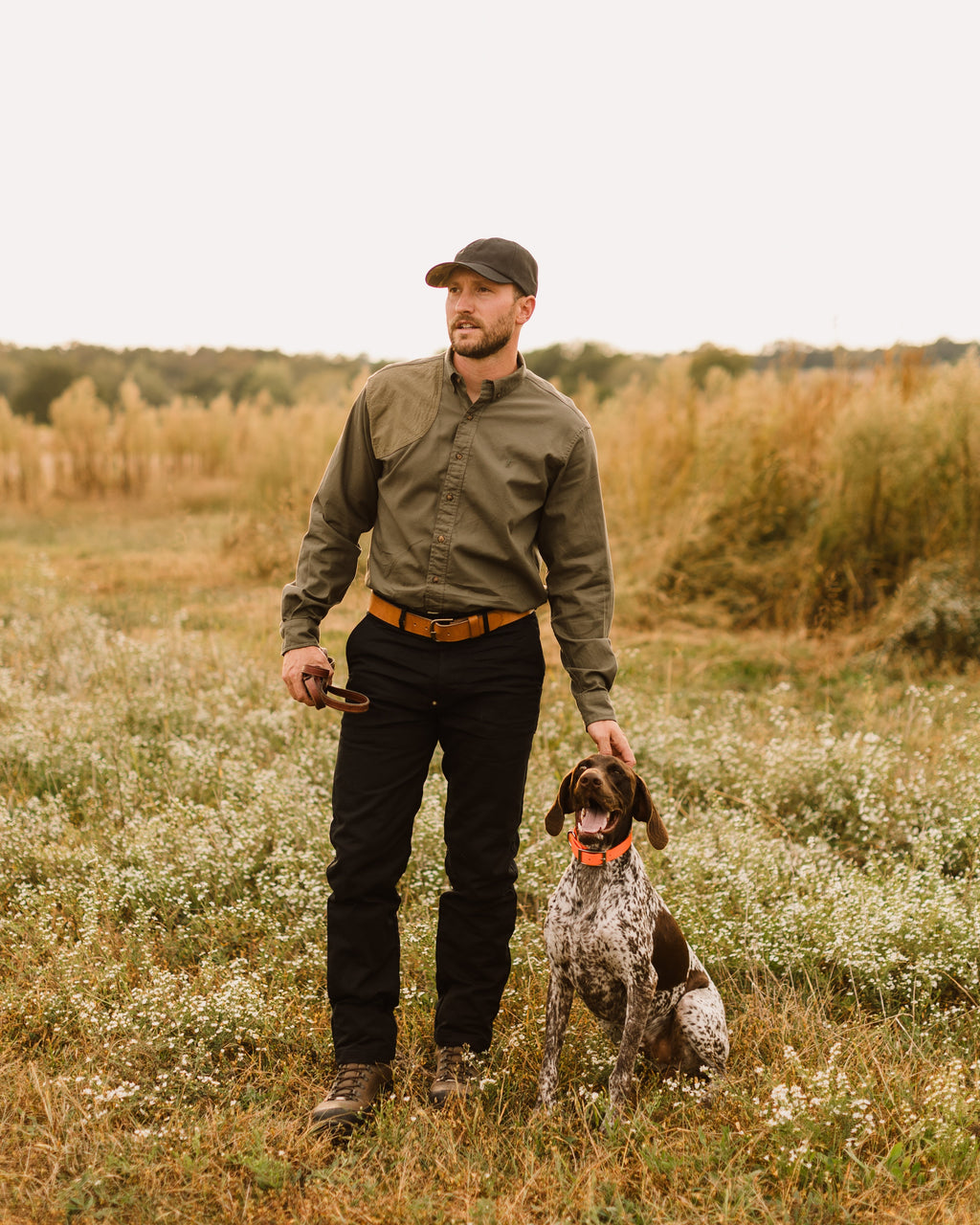 Hunter and German shorthaired pointer in a field, man wearing the Jack Carr Hunters Shirt