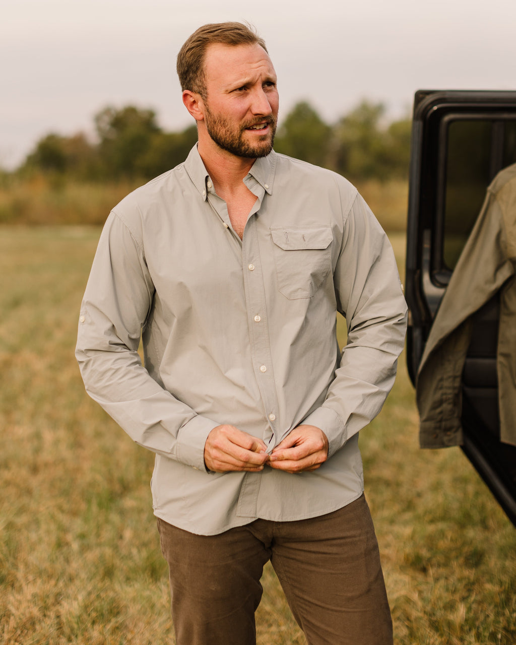 Man in a grey button-down and Heritage Pant standing by a truck door