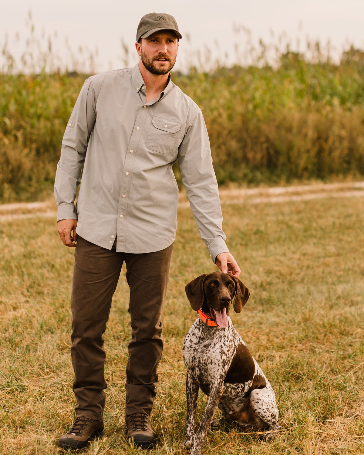 Man with a German shorthaired pointer in a field wearing the Heritage Pant