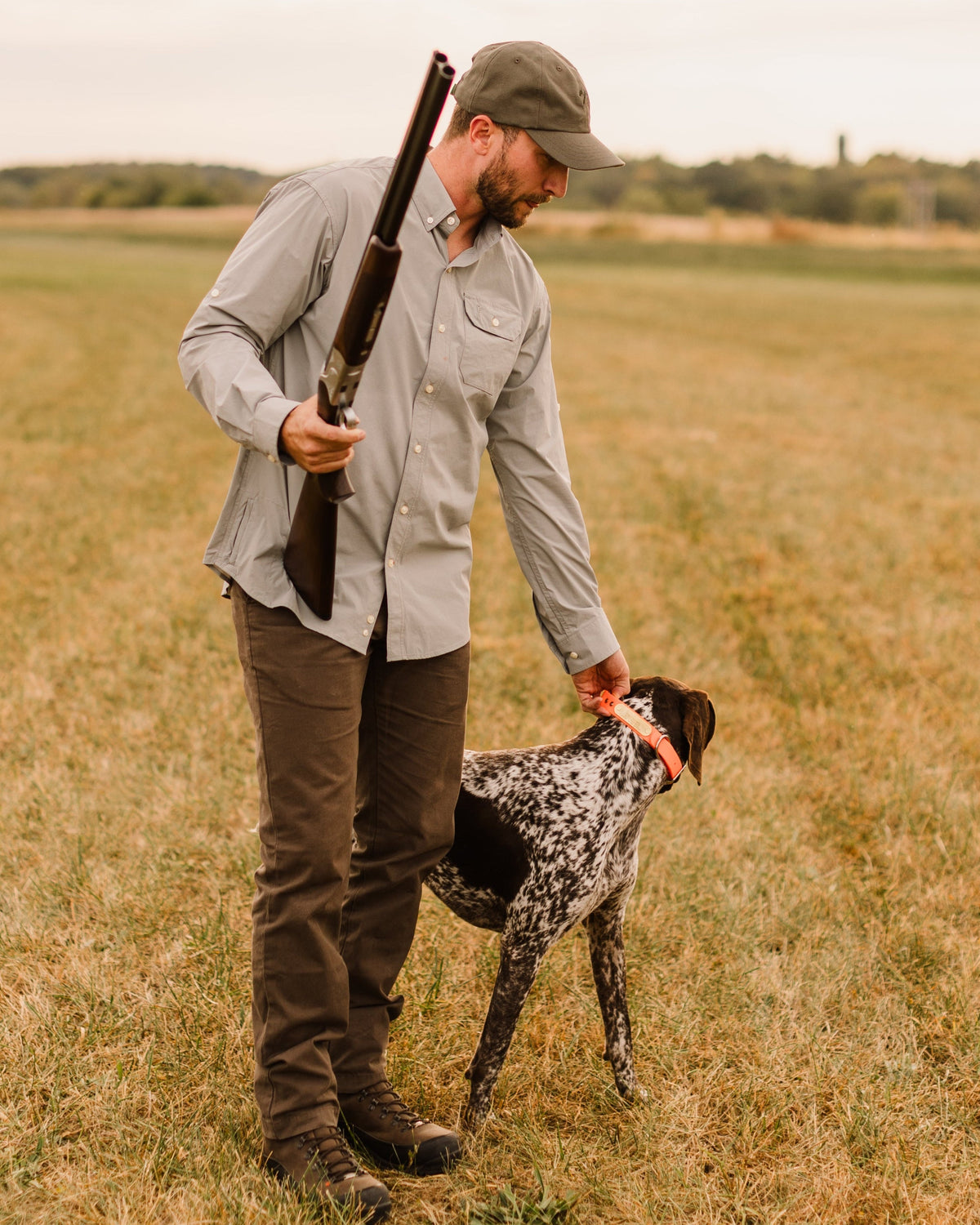 Man with a shotgun and pointing dog in a field wearing the Heritage Pant