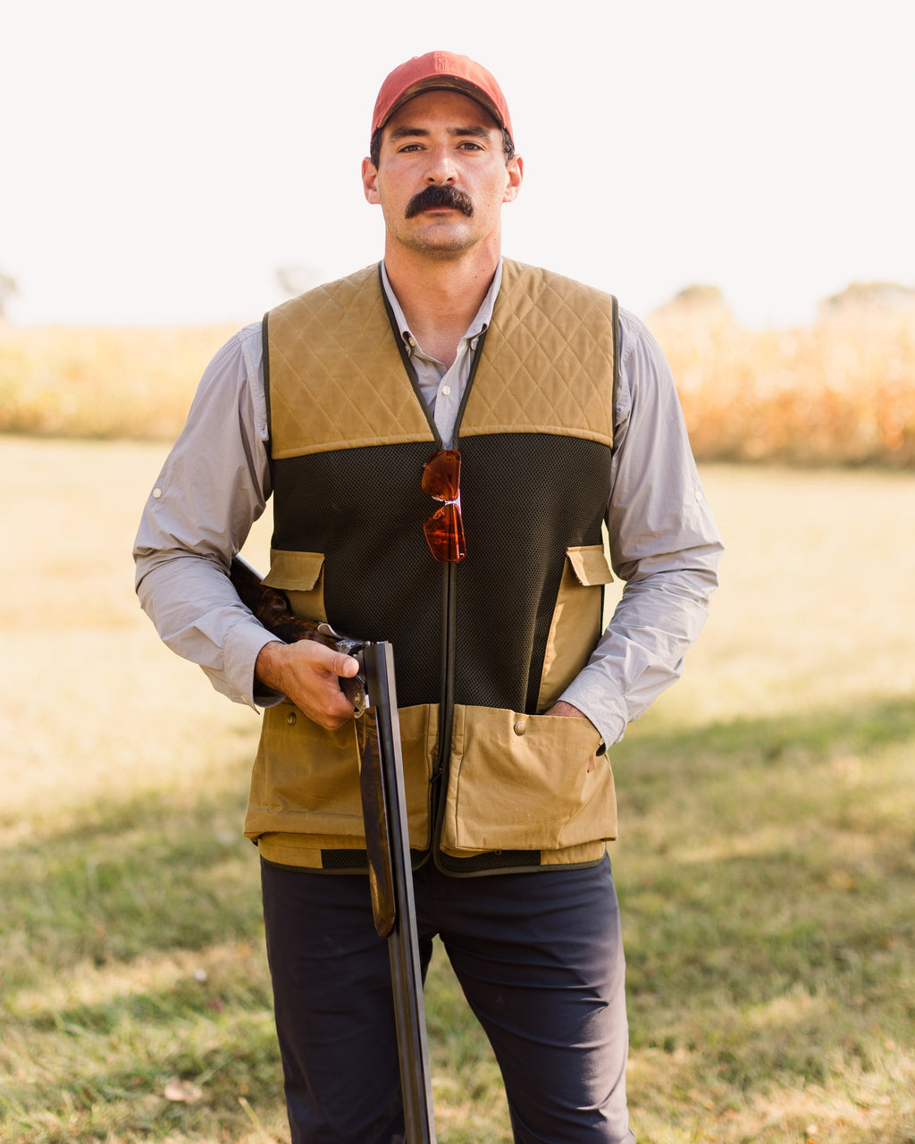 Heritage Clays Vest worn with a shotgun at the shooter's side in an open field