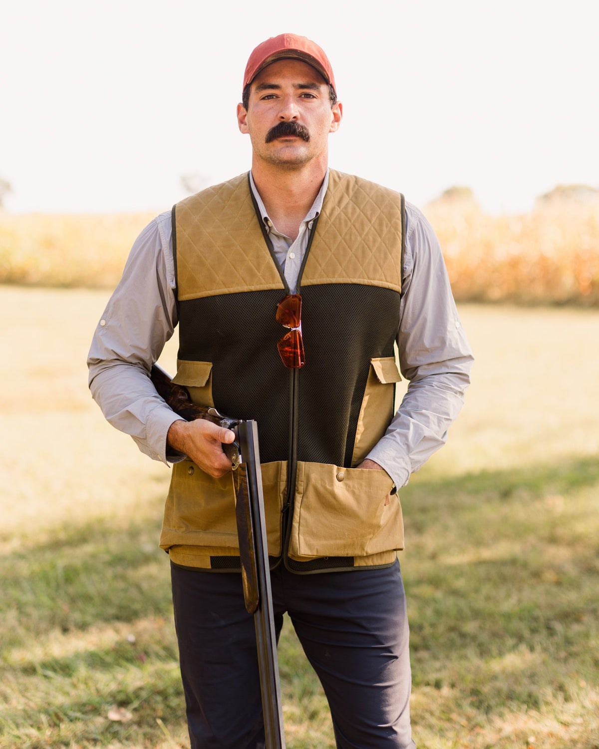 Heritage Clays Vest worn with a shotgun at the shooter's side in an open field