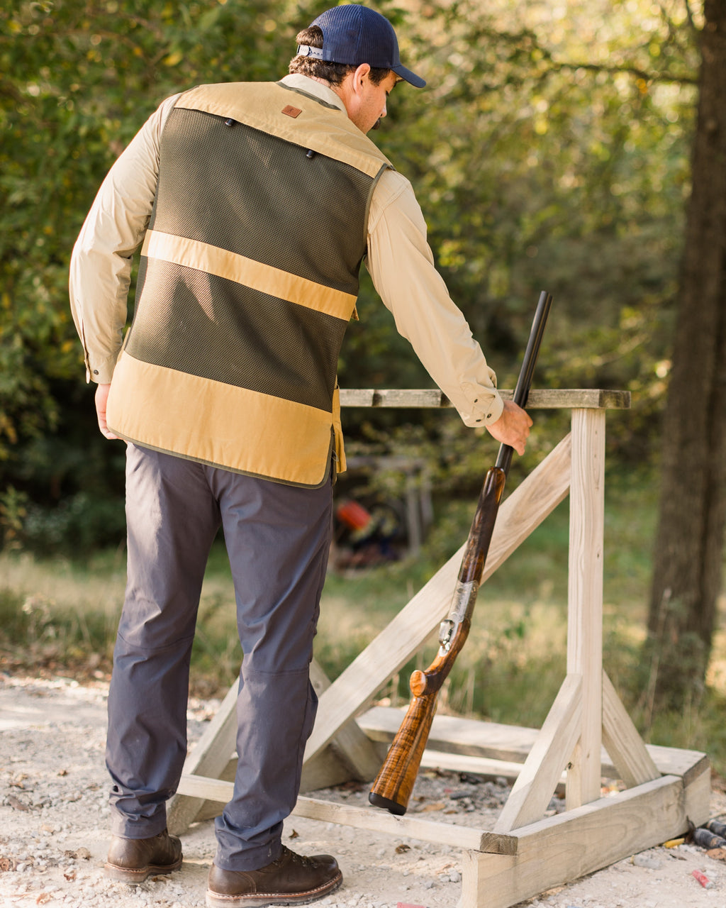 Shooter at a clays trap wearing the Heritage Clays Vest, rear three-quarter view
