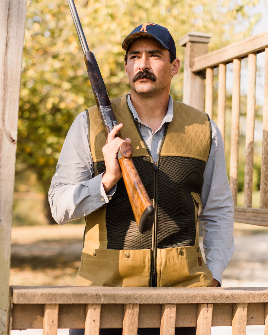 Shooter holding an over-under shotgun at a station wearing the Heritage Clays Vest