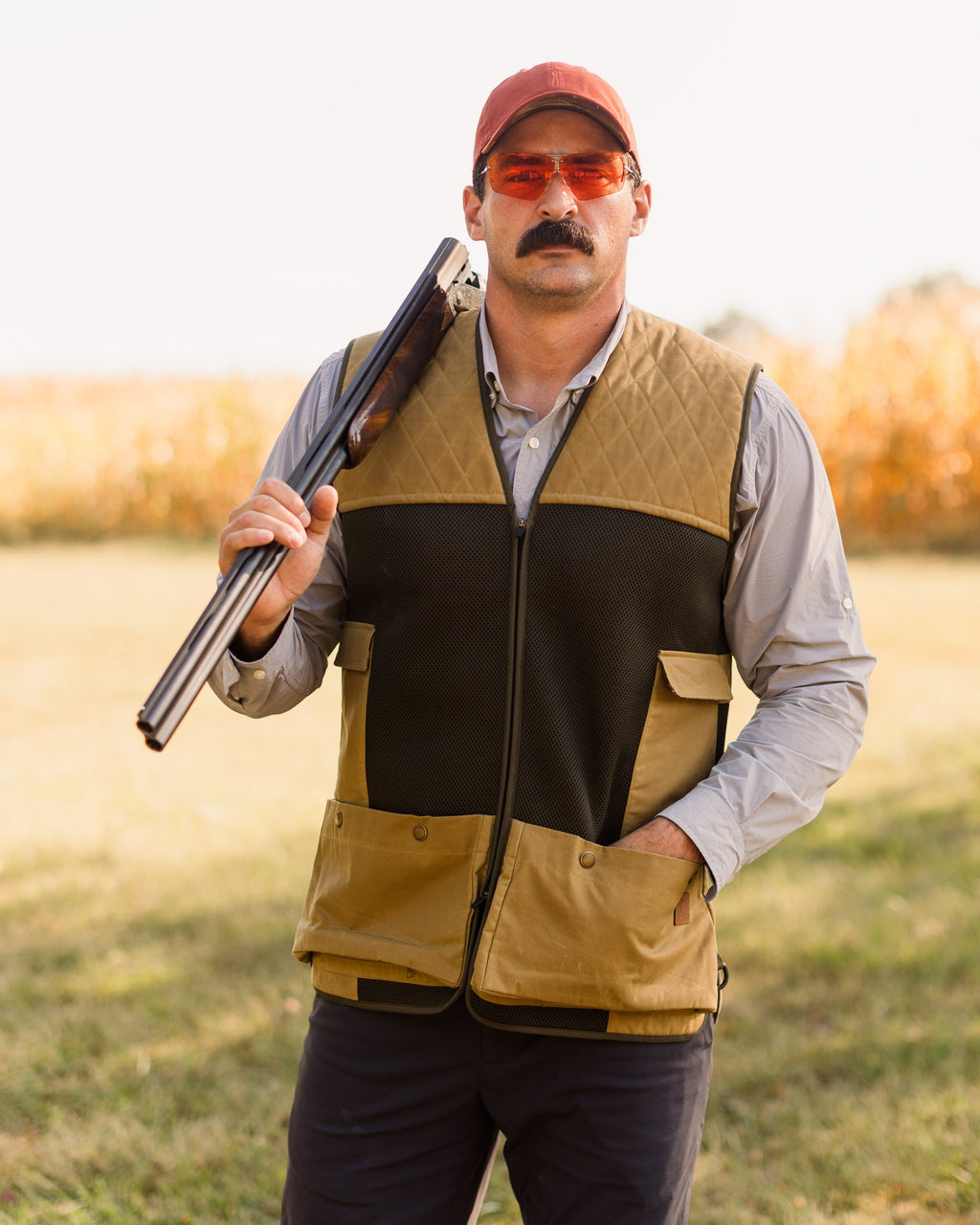 Shooter in a red cap carrying a shotgun while wearing the Heritage Clays Vest
