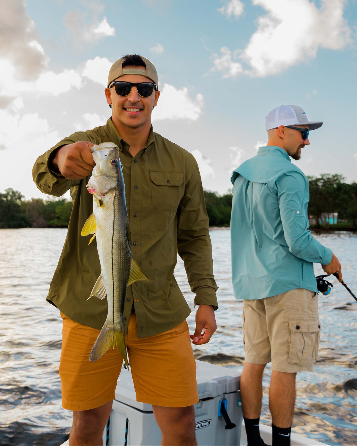 Angler holding a snook on a flats boat wearing the Olive Active+ Guide Shirt
