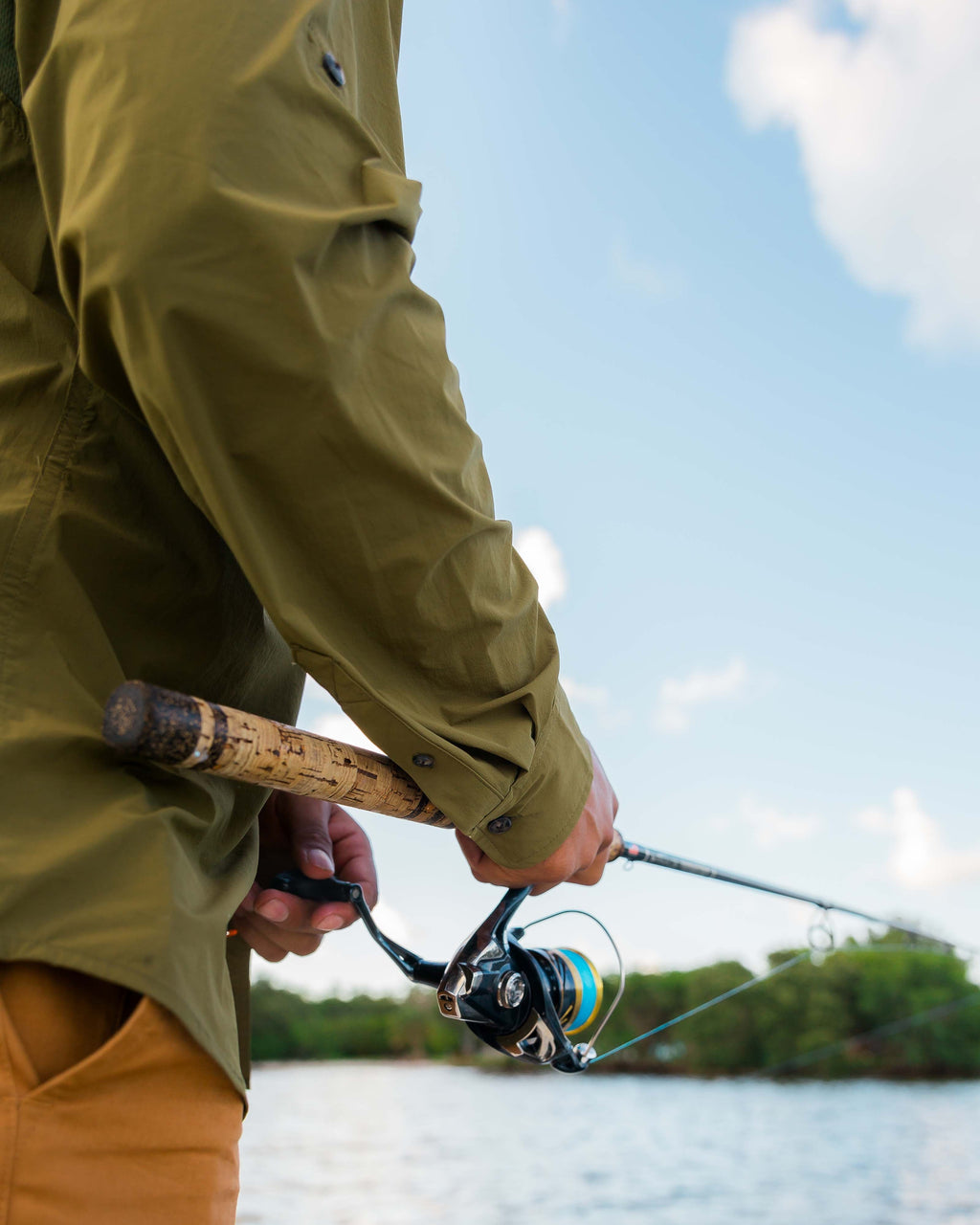 Angler in the Olive Active+ Guide Shirt fighting a fish with a spinning rod