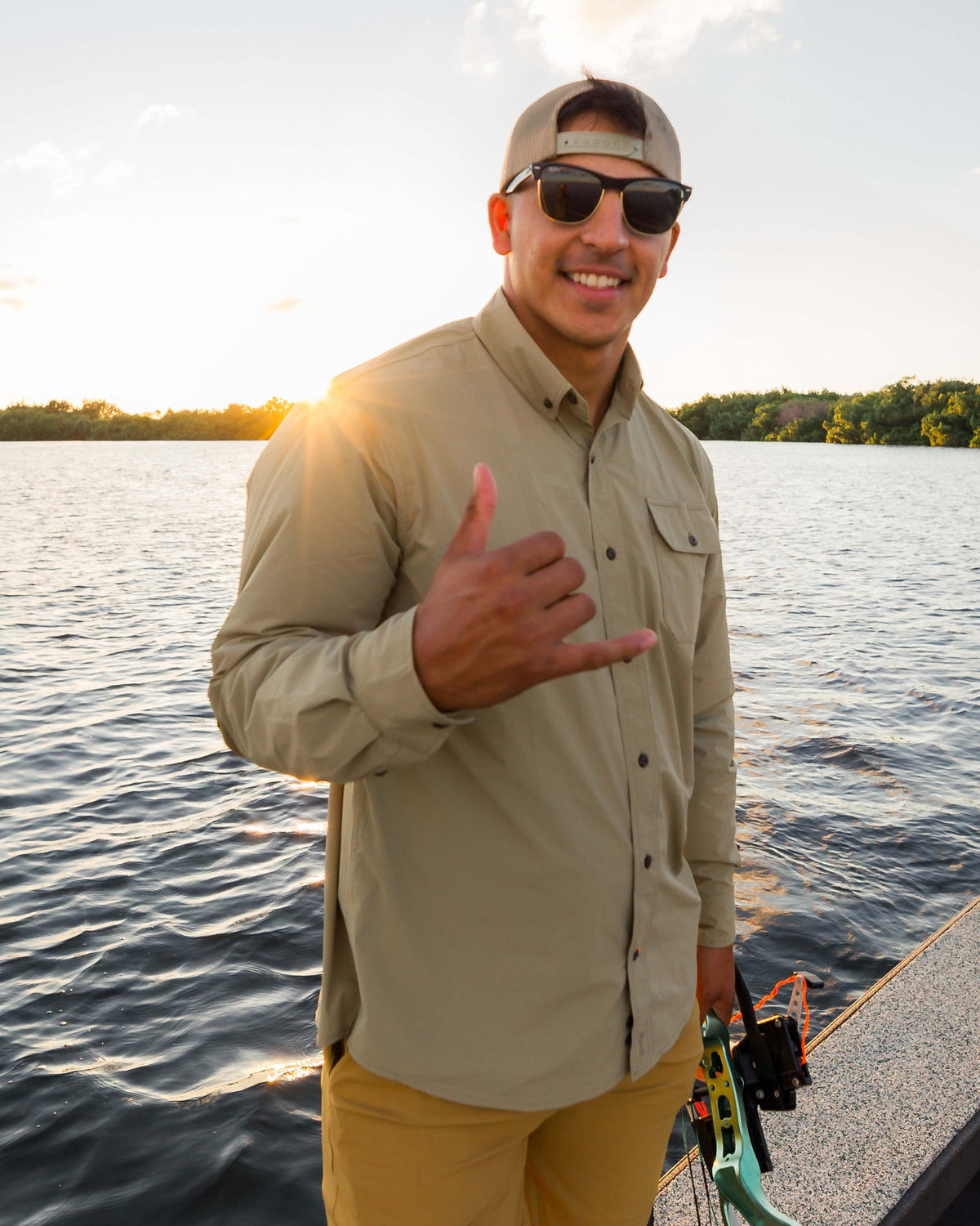 Angler on a boat at sunset wearing the Tan Active+ Guide Shirt