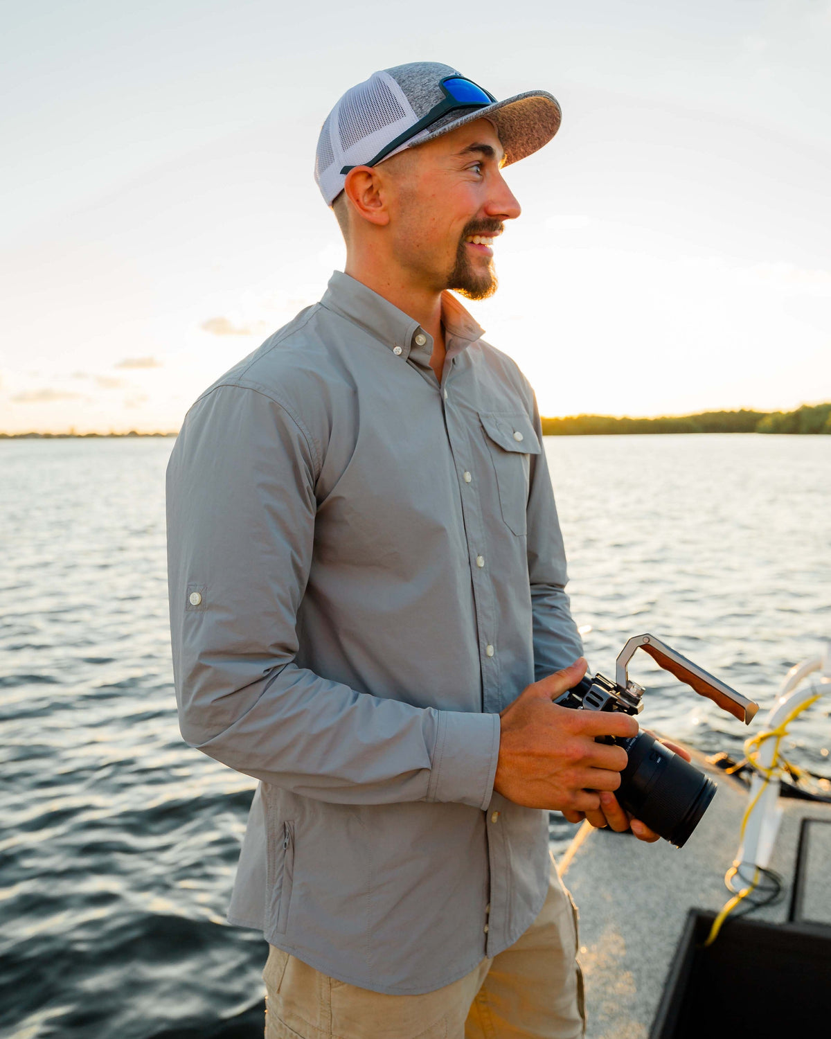Man on a boat at golden hour wearing the Sky Blue Active+ Guide Shirt