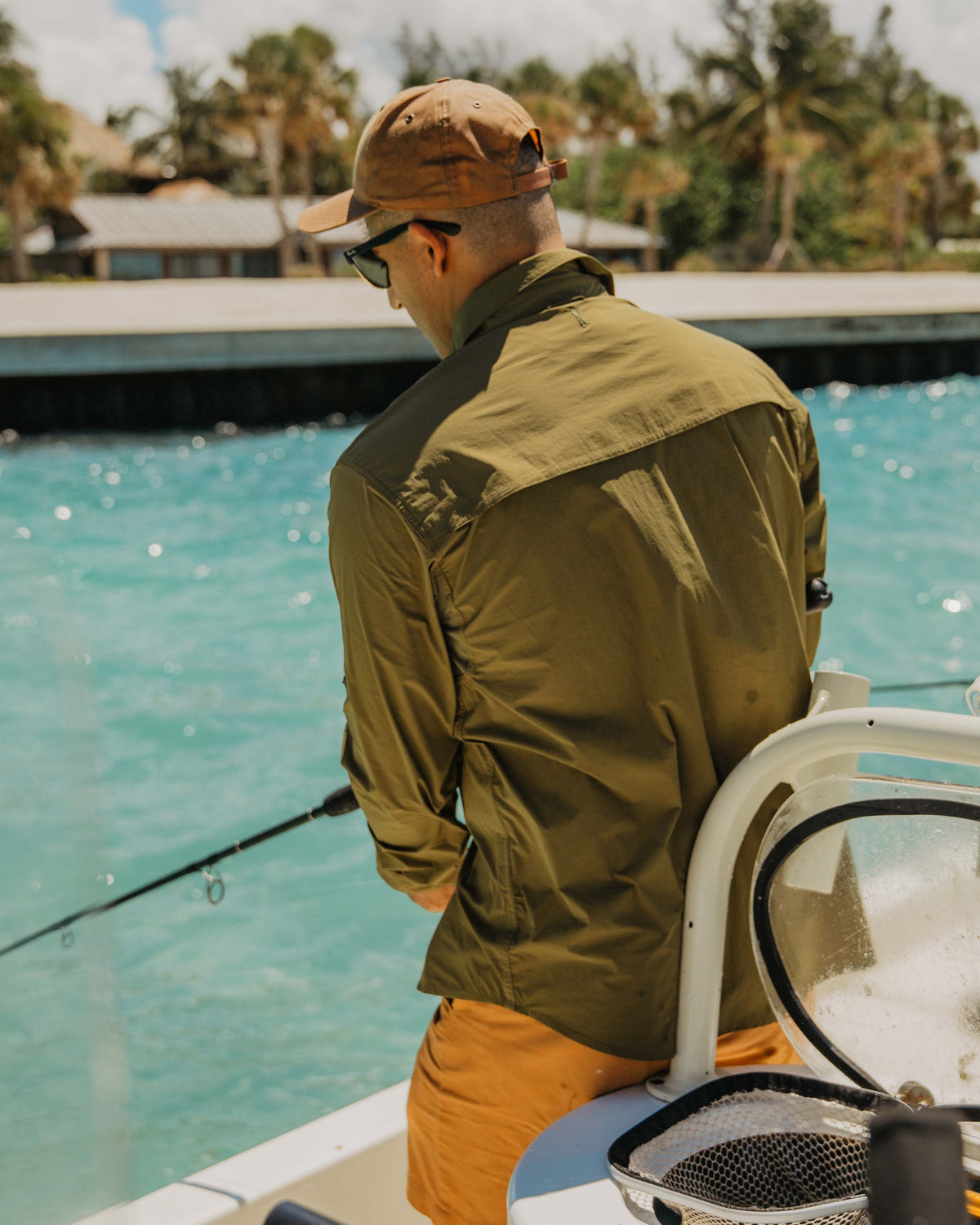 Angler casting from a boat in the Olive Active+ Guide Shirt