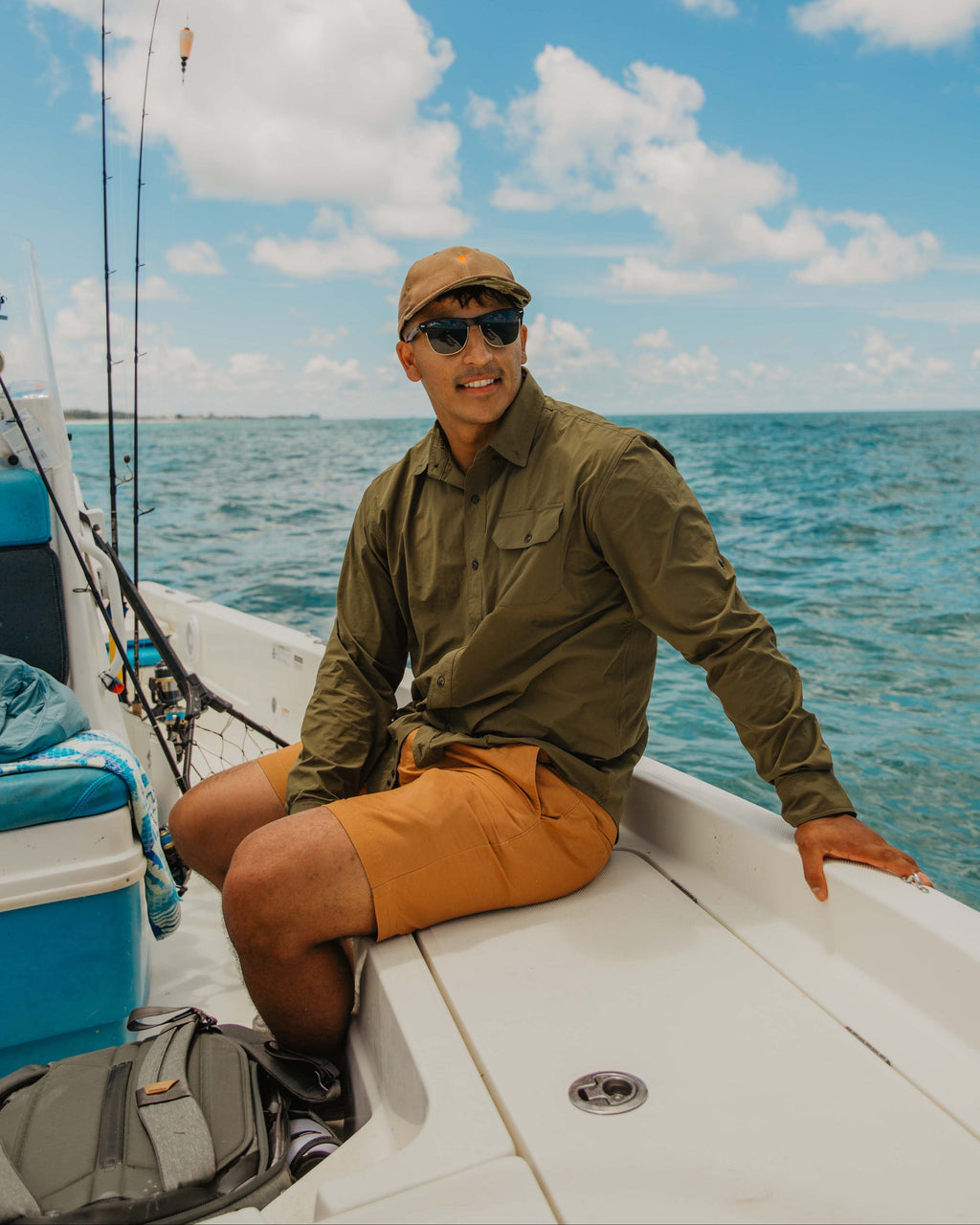 Angler seated on the bow of a skiff wearing the Olive Active+ Guide Shirt