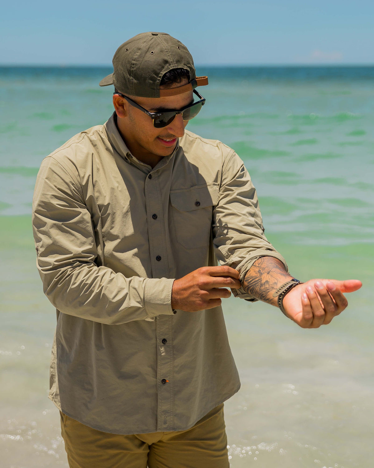 Man rigging a line on the beach wearing the Tan Active+ Guide Shirt