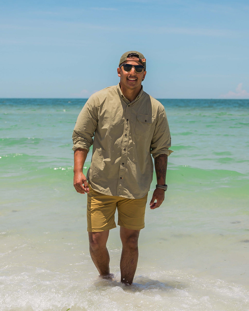 Man wading clear shallow water in the Tan Active+ Guide Shirt
