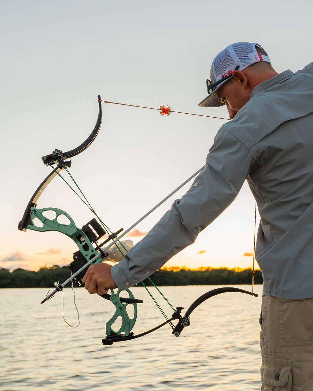 Bowfisherman drawing a bow on the water in the Sky Blue Active+ Guide Shirt