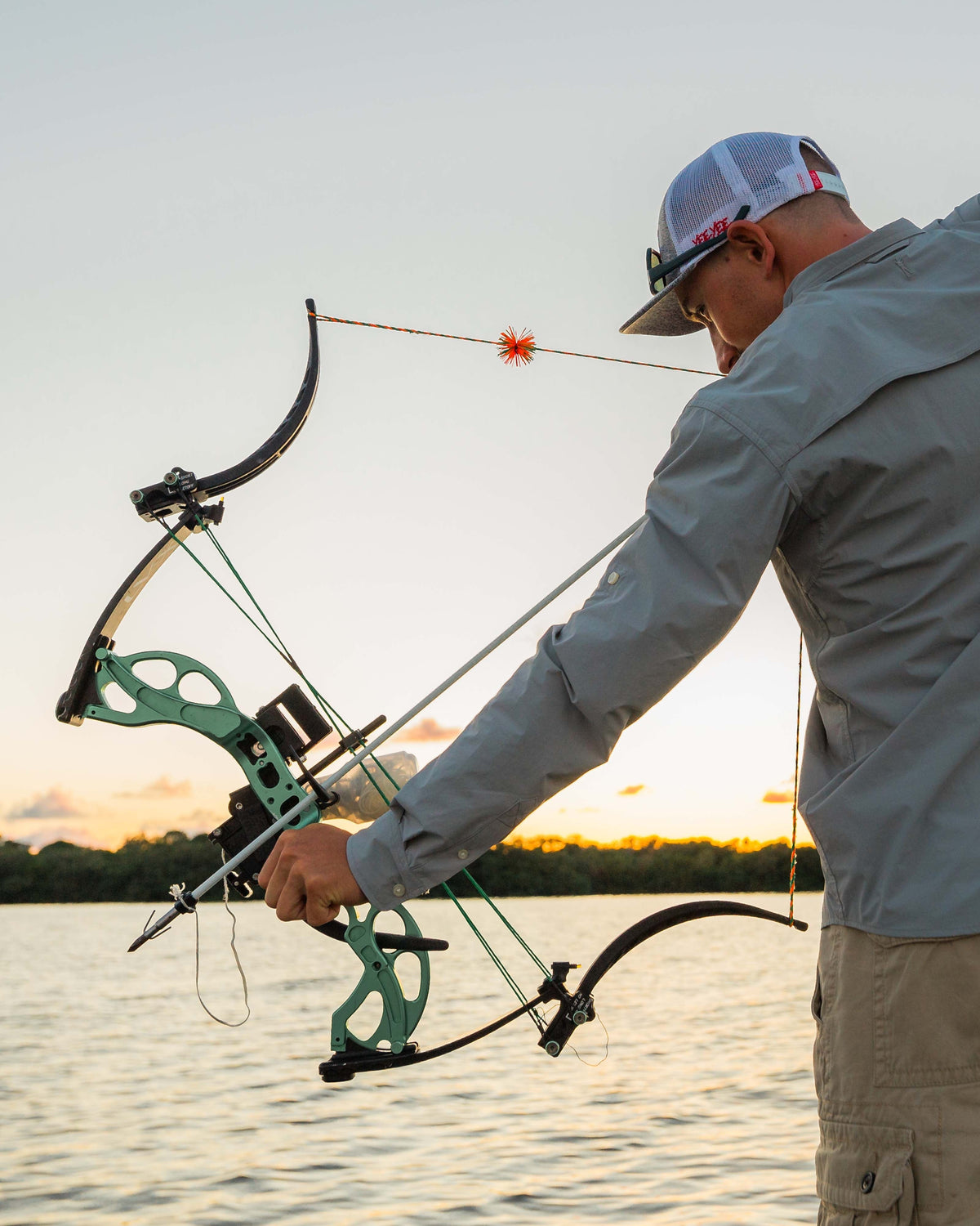 Bowfisherman drawing a bow on the water in the Sky Blue Active+ Guide Shirt