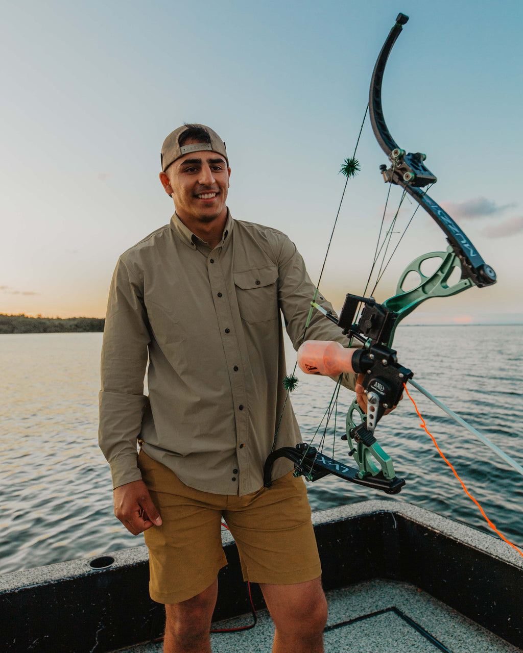Bowfisherman standing on a boat with a bowfishing bow in the Tan Active+ Guide Shirt