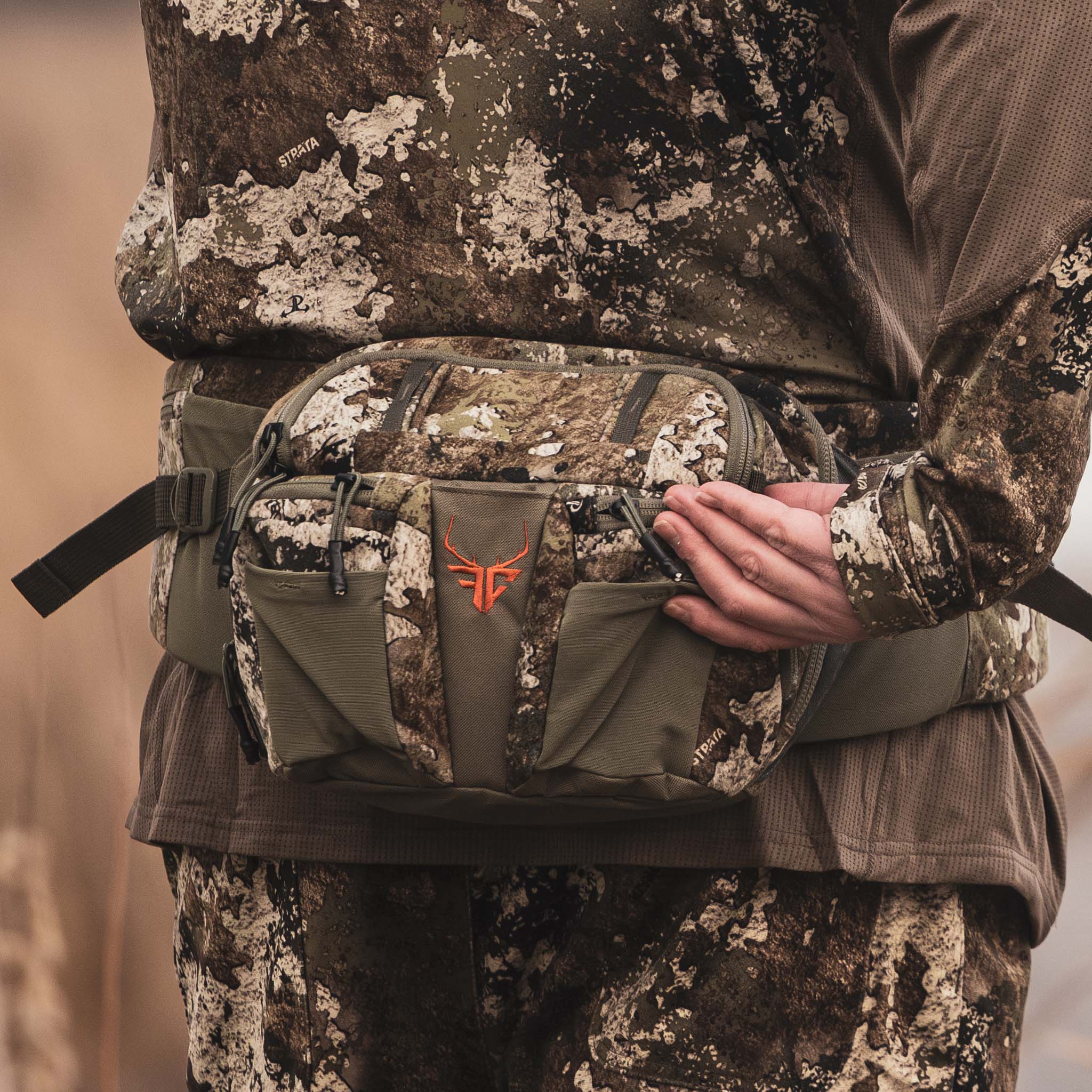 Strata camo hunting waist pack with orange logo, worn for outdoor gear storage