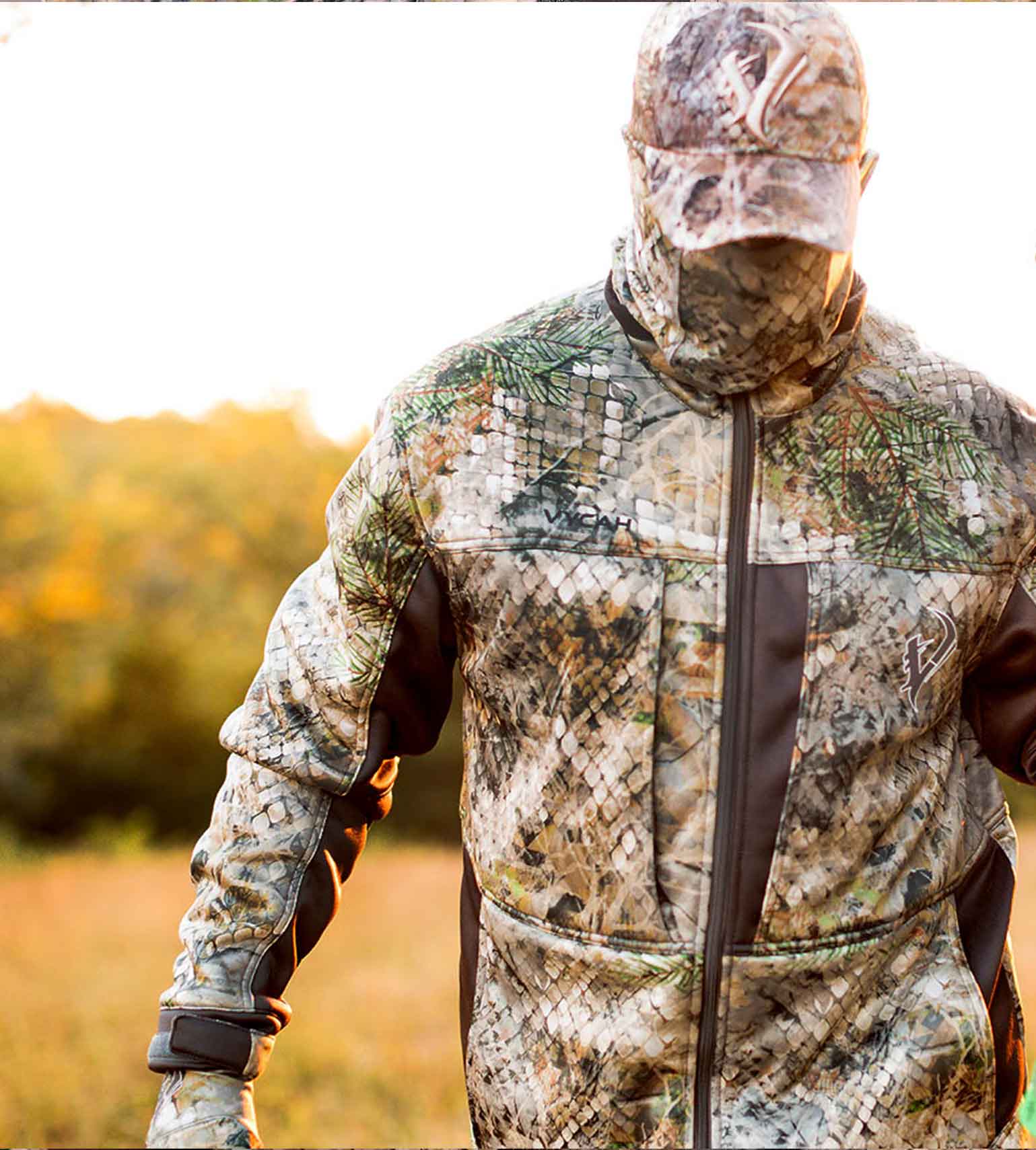 Hunter in a field wearing a Vycah Kinsley Jacket in Fall camo with a matching face mask