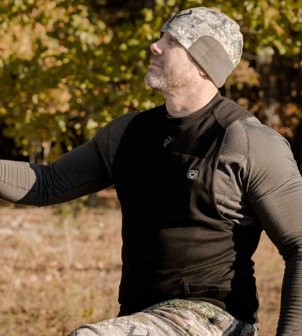 Hunter wearing a Vycah Oculus Heated Vest over a base layer with a camo beanie in fall timber