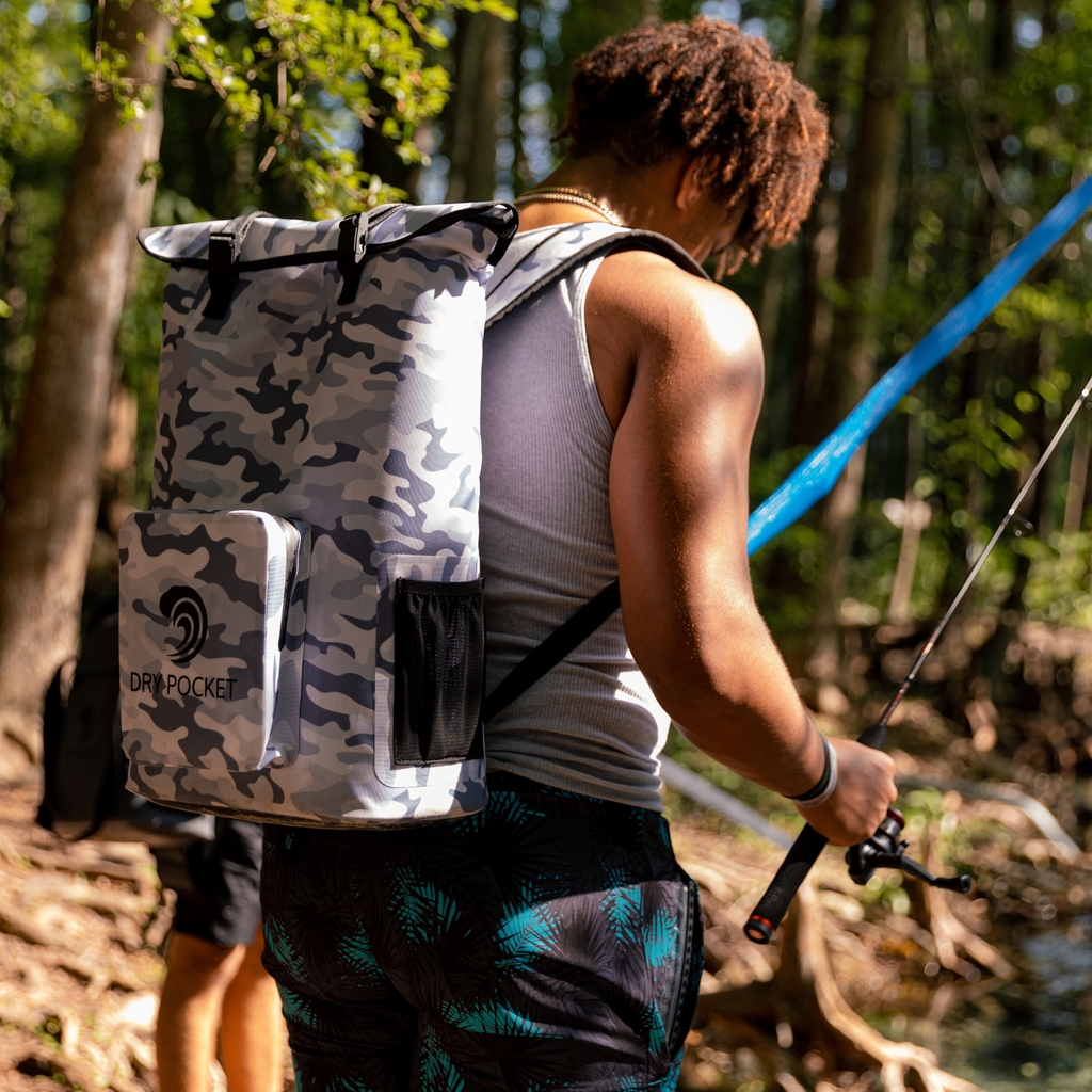 Camouflage dry bag backpack with dry pocket, worn while fishing in woods