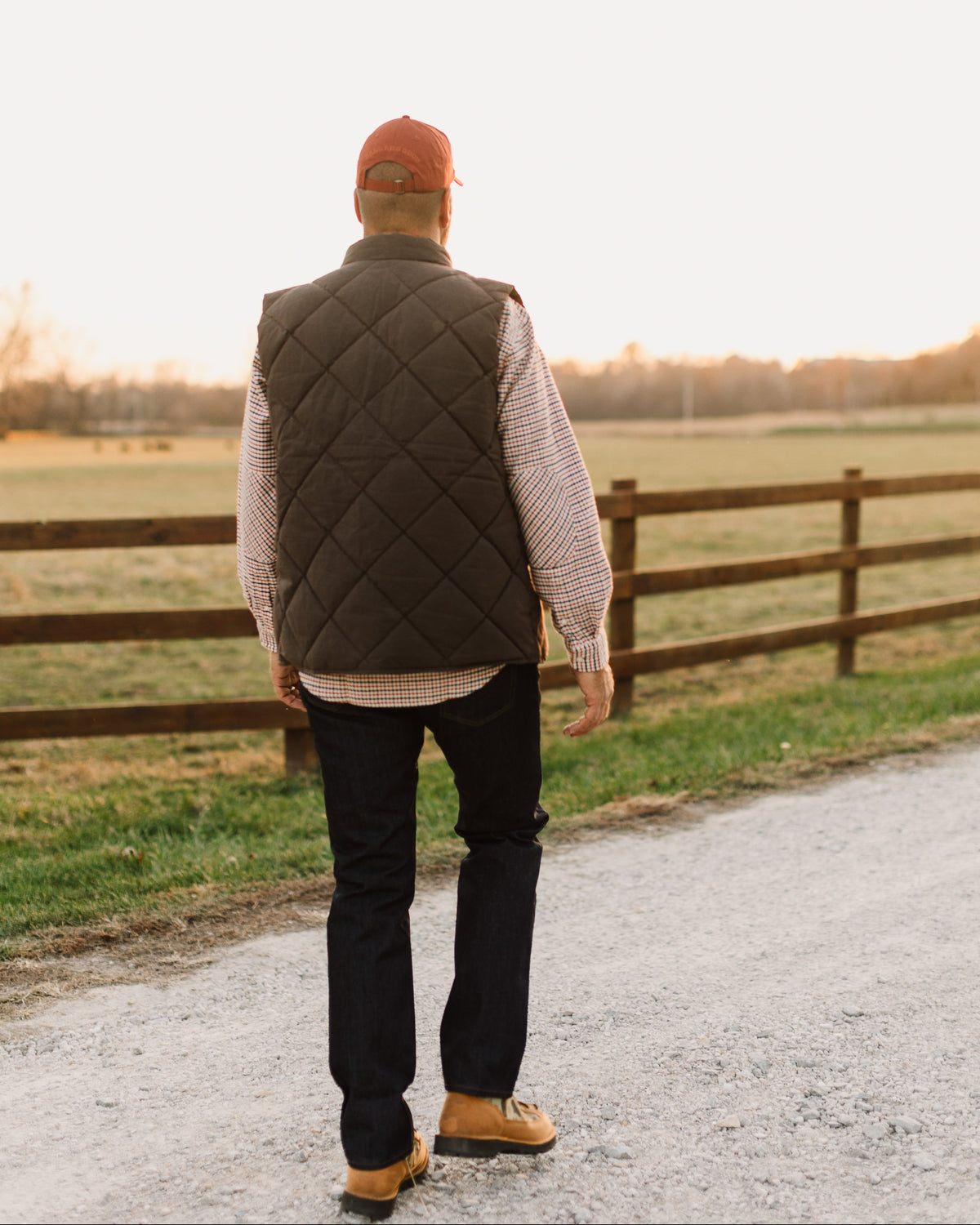 Back view of the Brown Arthur Down Vest worn on a gravel farm road
