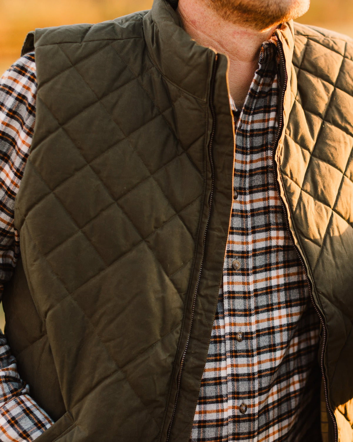 Loden Green Arthur Quilted Waxed Down Vest worn over a plaid flannel shirt