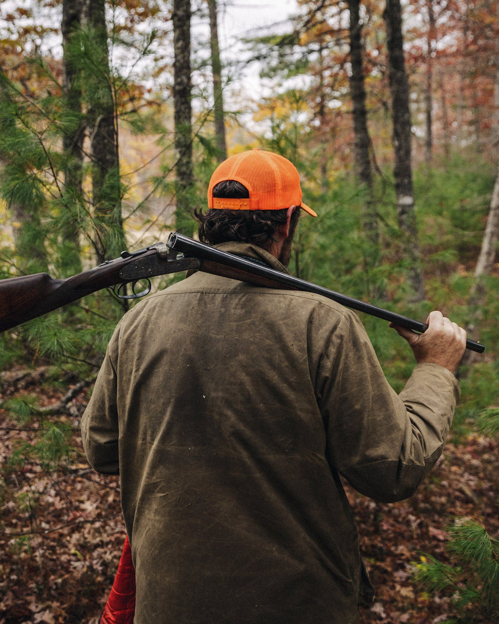 Hunter carrying a side-by-side in hardwood timber wearing the Olive Upland Jacket