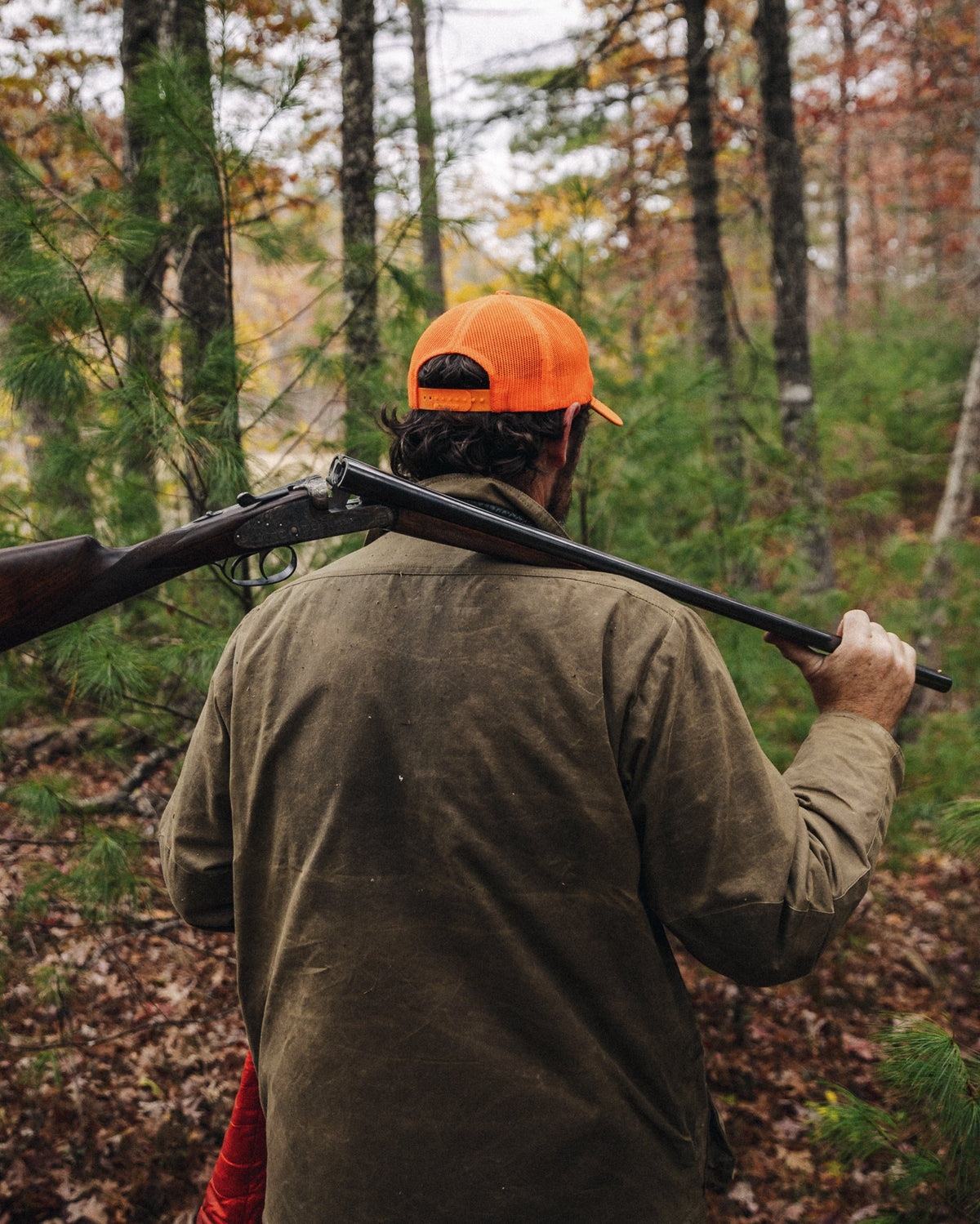 Hunter carrying a side-by-side in hardwood timber wearing the Olive Upland Jacket
