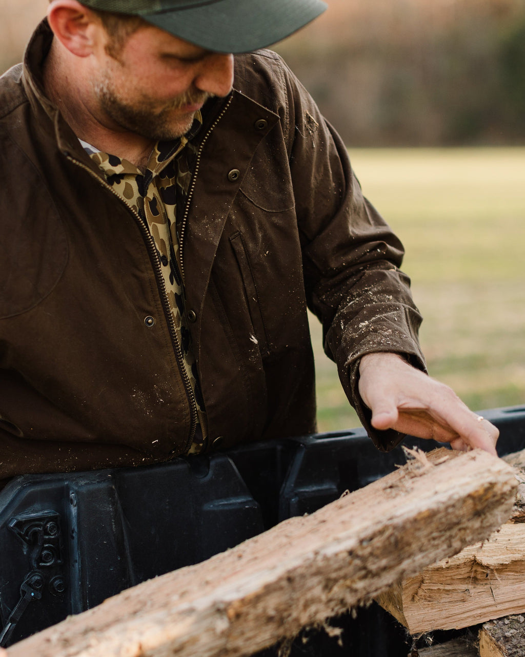 Man in the Oak Waxed Field Jacket loading split firewood into a UTV bed