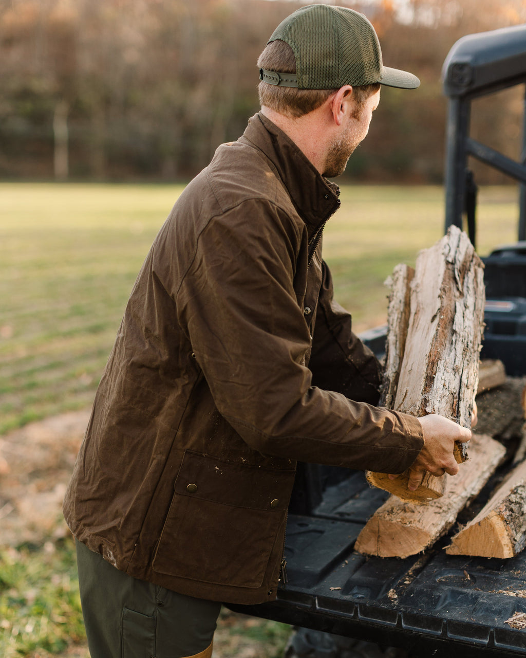 Oak Waxed Field Jacket worn while carrying firewood, side view