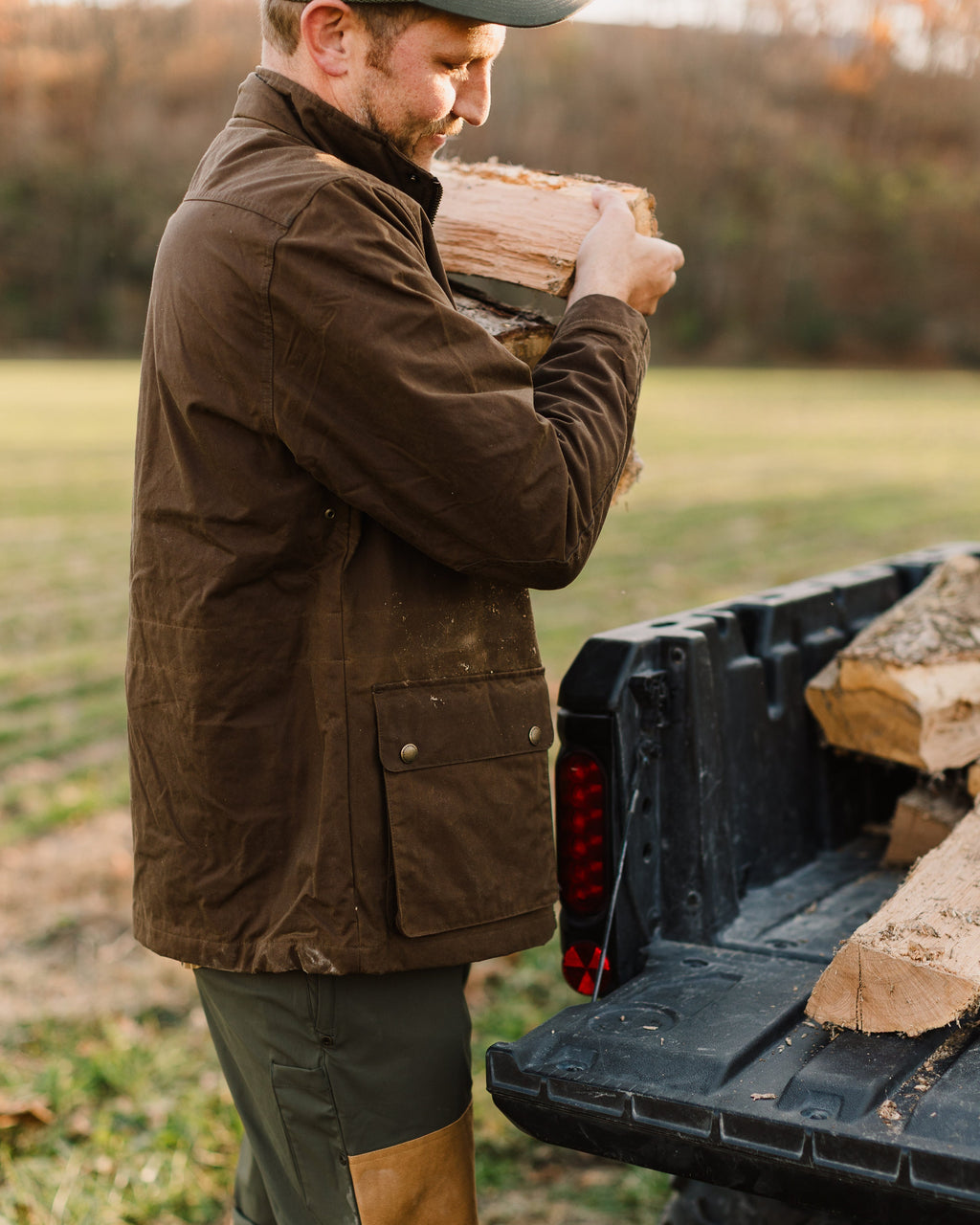Man in the Oak Waxed Field Jacket hauling an armload of split wood
